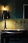 Halbdunkler Badausschnitt - Tischlampe mit glänzendem Schirm auf Waschtisch mit glänzender Oberfläche