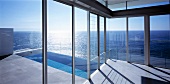 View of swimming pool and sea through glass wall