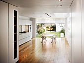 Grosszügiges Esszimmer mit moderner, offener Küche vor Terrasse