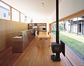 Living space with long, stainless steel counter and dining area in front of open wall leading to terrace