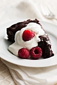 Slice of Gooey Chocolate Cake with Whipped Cream and Raspberries
