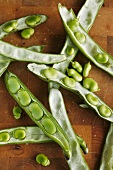 Broad beans and pods on a wooden surface