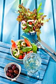 Two summer salads, olives and a glass of white wine