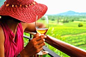 Frau mit einem Glas Rose betrachtet den Weinberg