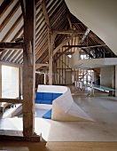 Deconstructivist installations in historic roof structure - sunken seating area with blue upholstery in front of panoramic window