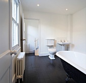 Traditionelles Bad in Altbauwohnung mit freistehender Wanne und Klauenfüssen auf schwarzem Fliesenboden