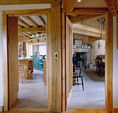 View through adjacent wooden doors into country-style kitchen and rustic dining room with fireplace