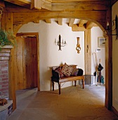 Rustic foyer with patterned cushions on antique wooden bench