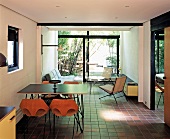 Moderner Wohnraum mit Möbeln im Fifties-Stil auf braunen Fliesen und Blick in den Bambusgarten