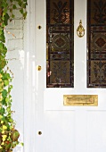 weiße, antike Haustür mit farbigen Bleiglasfenstern und Messing-Briefschlitz