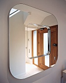 Square mirror with rounded corners reflecting front door