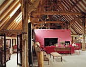 Antique pieces and pink wall with fireplace in old, converted barn