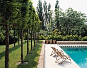 Landscaped garden with wooden deckchairs next to swimming pool