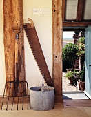 Antique farmyard implements in front of half-timbered beams and open door leading to garden