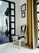 Ecke in einer Diele mit originellem Stuhl und hellenistisch gemustertem Vorhang