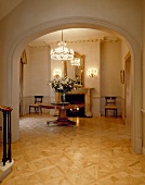 Villa foyer with parquet floor and view of antique table through rounded arch