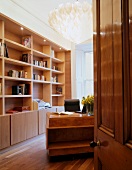 Blick durch offene Tür auf Wandbücherregal aus Holz im Wohnzimmer