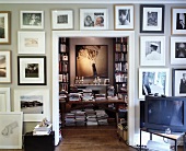 Wall with framed collection of pictures around open doorway with view of library