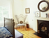 Armchair with delicate metal frame and upholstered seat in corner of traditional bedroom