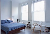 Bed with grey bed linen and 50s armchair in modern bedroom