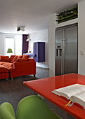 Grüner Sessel an orangem Tisch vor Loungebereich in modernem Wohn - und Esszimmer