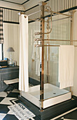 Glass shower stall with brass frame in a bathroom with a black and white floor