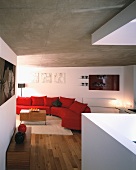 Living space with curved red couch below grey concrete ceiling