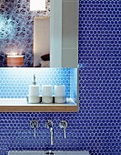 Mirrored cabinet with indirect lighting and shelf on wall with blue mosaic tiles