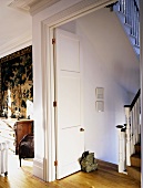 Blick durch offene, weiss lackierte Flügeltür ins traditionelle Treppenhaus