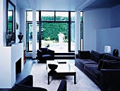 Black sofa set in white, modern living room with view of terrace