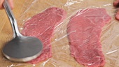 Flattening a veal escalope wrapped in cling film