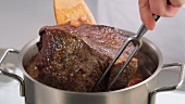 Pouring red wine over beef for braising