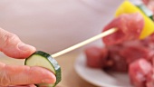Threading cubes of meat and vegetables onto a wooden skewer