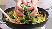 Brokkoli mit dem anderen Gemüse im Wok vermengen