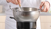 Placing round-bottomed metal mixing bowl over pan of simmering water