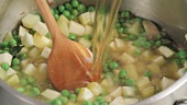 Pouring stock into pea soup