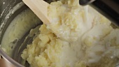 Gestampfte Kartoffeln mit Milch vermischen