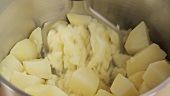 Gekochte Kartoffeln mit einem Kartoffelstampfer zerdrücken