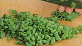 Chopping spring onion leaves into fine rings