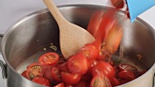 Placing cherry tomatoes in a saucepan