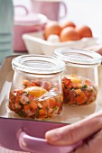 Chopped vegetables and raw egg in glass jar
