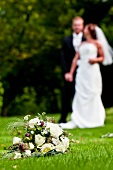 Bridal bouquet on lawn, bride and groom in background