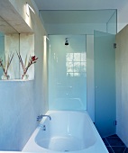 Bathtub with adjacent shower area and glass partition with open glass door