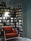 Decorative, dark book alcove with stylish, red upholstered armchair