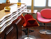 Hotelbar im Retrostil mit Schalensitzen in peppigen Farben am kleinen Tisch