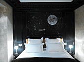 Themed hotel room with stylised night sky on wall behind double bed