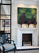Moderne Kunst und Blumensträuße über brennendem Kamin im eleganten Wohnzimmer