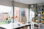 Dining area with simple, modern furniture and children's playthings in front of glass wall leading to courtyard garden