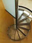Exquisite, contemporary spiral staircase with metal treads in wood-panelled, cylindrical stairwell