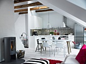 Open-plan attic room in youthful Scandinavian style with simple kitchen, dining area and wood burner